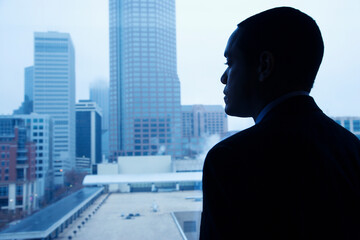 Fototapeta premium African-American businessman looking out of a window at the city. Horizontal shot.