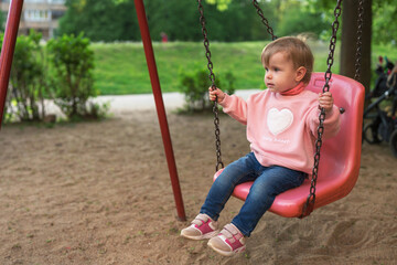 Little girl sitting on a swing