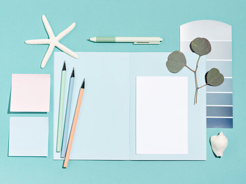 Minimal layout with pastel blue, pink and cyan colours. Compositions of stationary, cards and envelopes. Blank white card in the middle is a template for invitation, greeting or business card.