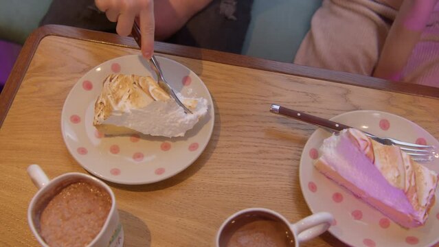 Top view of a girl eating meringue cake at the restaurant. Stock footage. Enjoying sweet cake and cocoa.