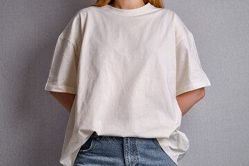 Woman in a white T-shirt poses near a white wall. Hand gestures and emotions. Studio photography....