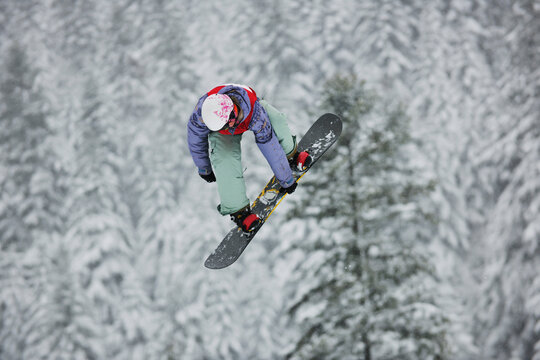 young boys jumping in air ind showing trick with snowboard at winter season