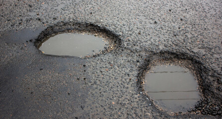 Deep pit on the road. Damaged asphalt.Puddles in potholes on the road. Damaged highway.Pit in the asphalt, destroyed road, destroyed road surface,