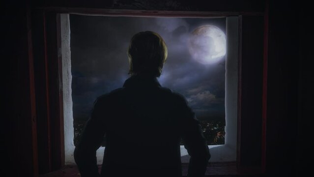 Man Silhouette Window Moonlight City Skyline Zoom In. Silhouette of a man looking through a window to the full moon above the city. Zoom in