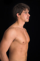 Naklejka premium portrait of young man standing with no shirt on over black background