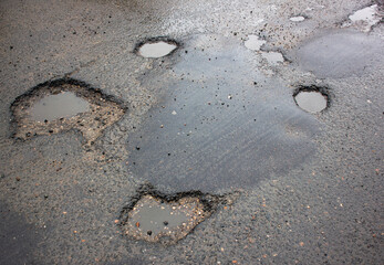 Deep pit on the road. Damaged asphalt.Puddles in potholes on the road. Damaged highway.Pit in the asphalt, destroyed road, destroyed road surface,