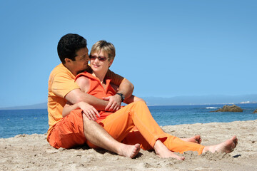 Fototapeta premium Happy couple in orange clothes on the beach