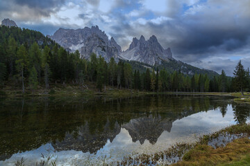 Fototapeta na wymiar Lake Antorno in the Italian Dolomites with reflection of mountains in the water. There are beautiful clouds in the sky. You can see the road to Tre Cime.