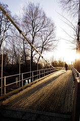 A beautiful day with the sun shinning into the camera over a suspension bridge.