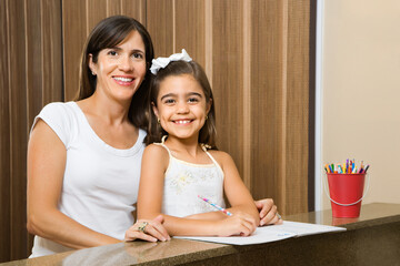 Hispanic mother and daughter portrait with homework.