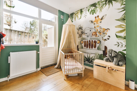 Fototapeta a baby's room with animals on the wallpaper and wooden furniture, including a cribe bed
