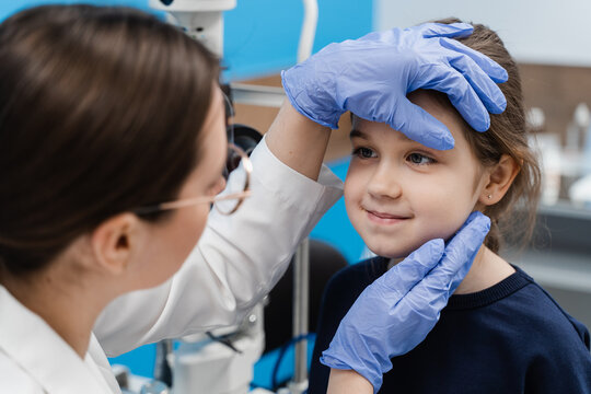 Pediatric Ophthalmologist Examines Eyes And Pupil Of Child. Consultation For Children At Ophthalmological Clinic For Treatment Of Eye Inflammation And Vision Correction.