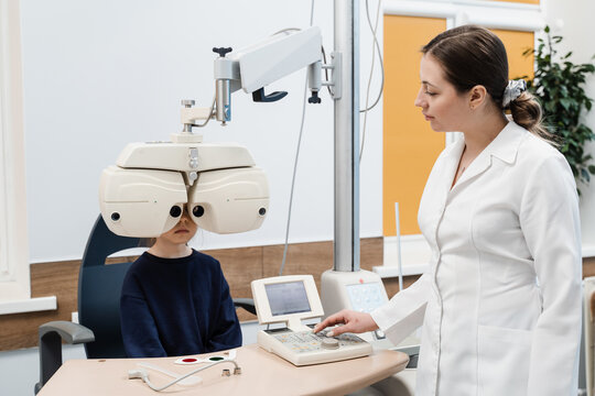 Phoropter for measuring refractive error and determining information for prescription for eyeglasses. Child looks into phoropter during an eye examination of pediatric ophthalmologist.