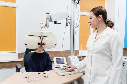 Phoropter for measuring refractive error and determining information for prescription for eyeglasses. Child looks into phoropter during an eye examination of pediatric ophthalmologist.