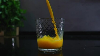 orange juice is poured into glass on gray background in the kitchen. Concept of a drink for breakfast and healthy food that gives energy