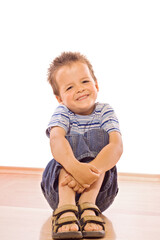 Boy sitting on the floor with a big grin on his face - isolated