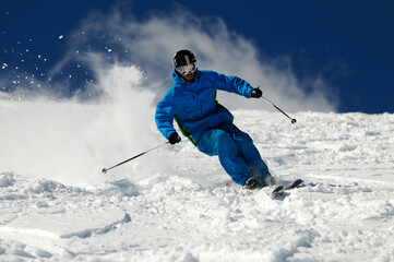 Fototapeta na wymiar Skier moving down on ski slope against blue sky.