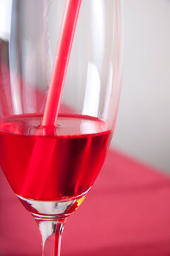 Red cocktail in a glass with a straw