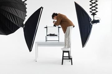 Capturing the artistic process. Full length shot of photographer guy standing on ladder and taking...