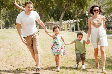 Family running with two young children at the park