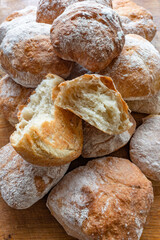 A pile of freshly baked ciabatta white crusty home-made rolls on a rustic wooden table, Top view,...