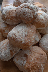 A pile of freshly baked ciabatta white crusty home-made rolls on a rustic wooden table, Top view, Side view.
