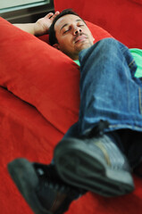 Fototapeta premium young man relax on red sofa and work on laptop at home indoor