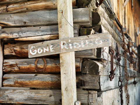 'GONE RIDING' sign against an old weathered, wooden stable. Horizontal shot.