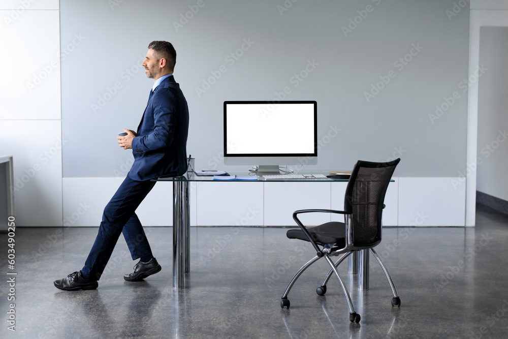 Poster successful businessman in formalwear sitting leaning on table with blank computer monitor mockup, co