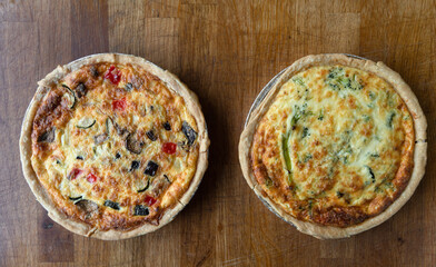 Quiche. Fresh eggs mixed with vegetables, bacon, ham, sausage, cheese, and Broccoli. The round shape on rustic wooden board.