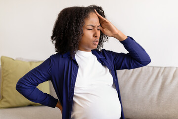 Sad despaired millennial black pregnant woman with big belly suffer from headache and health...