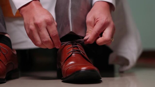 Ejecutivo visti&eacute;ndose, amarrando un zapato.