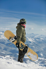 snowboarder relaxing and posing at sunny day on winter season with blue sky in background