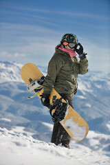 snowboarder relaxing and posing at sunny day on winter season with blue sky in background