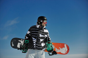 snowboarder relaxing and posing at sunny day on winter season with blue sky in background