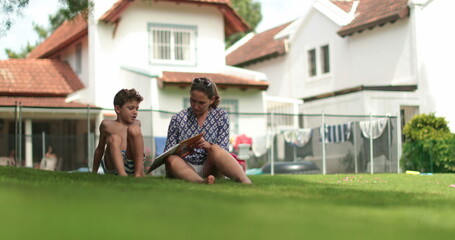 Fototapeta premium Candid mother studying homework with child son outside