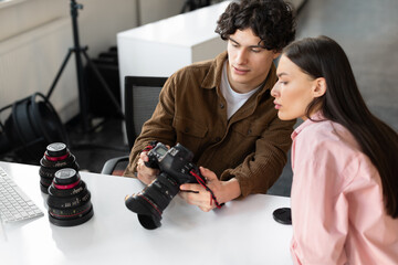 Picture review. Photographer man and yougn female model discussing shots after photoshoot in studio