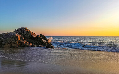 Surfer waves turquoise blue water rocks cliffs boulders Puerto Escondido.