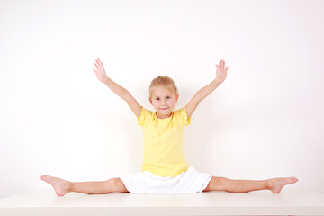 Cute little girl making splits on white background