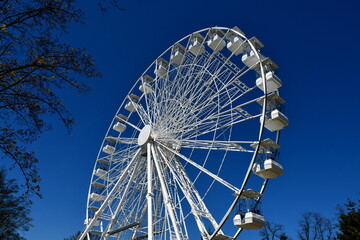 A close up on a white metal ferris wheel located in the middle of a theme park in Poland with...