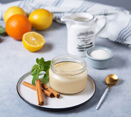 Delicious panna cotta or vanilla pudding with citrus fruits in a jar on a light background with  ingredients. Homemade healthy sweet food
