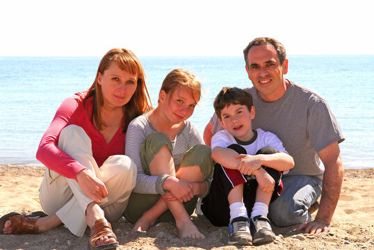 Portrait of a happy family of four sitting on a sandy beach