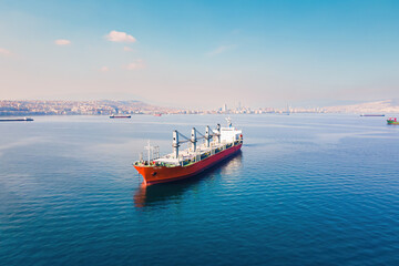 Cargo bulker ship waiting uploading stay at anchor near port. Aerial shot