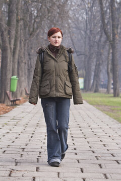 Redhead teen walking in an autumn park.