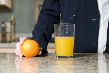 Stock photo of a woman wearing a business suit standing in kitchen with a glass of orange juice and...