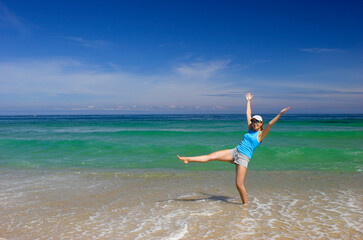 Fototapeta na wymiar Beautiful happy woman spreading water on the beach