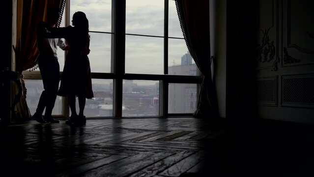 silhouette of dancing couple, young woman and man rehearsing waltz for wedding day