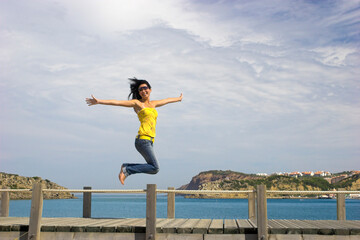 Young and beautiful woman jumping on a beach background