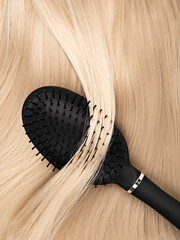 Close up of shiny long blonde straight hair with healthy structure and hairbrush. Process of salon...