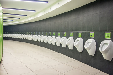Men's room with white porcelain urinals in line. Modern clean public toilets with tiles 